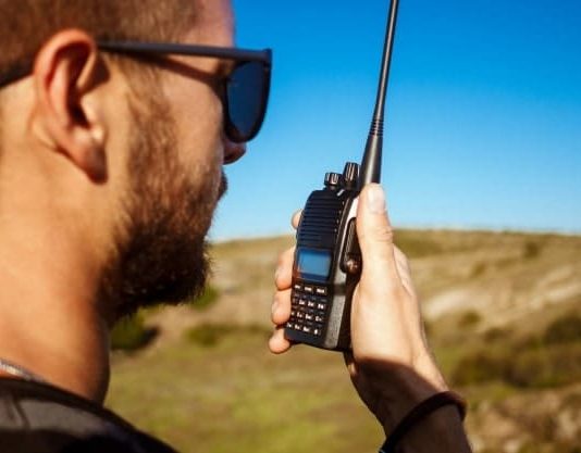 What Is The Best Emergency Communication? man talking walkie talkie radio enjoying canyon
